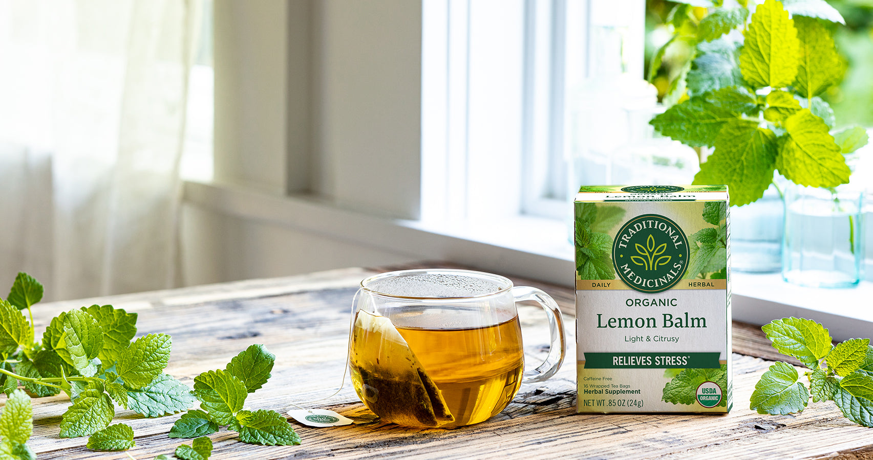 Lemon Balm tea in cup and packaging on table near window